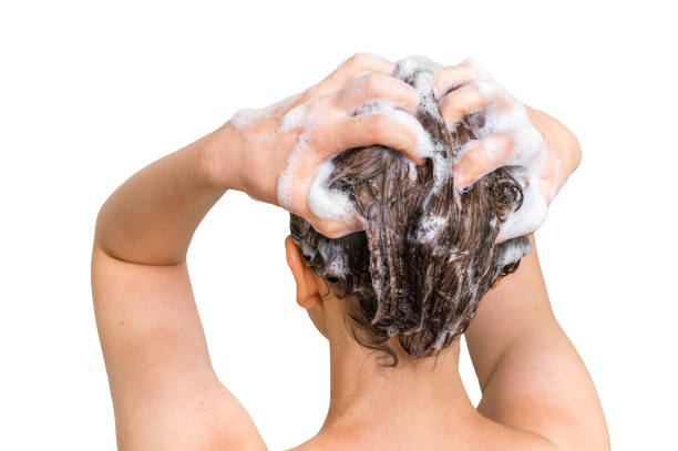Mujer lavándose el cabello con champú en la ducha.