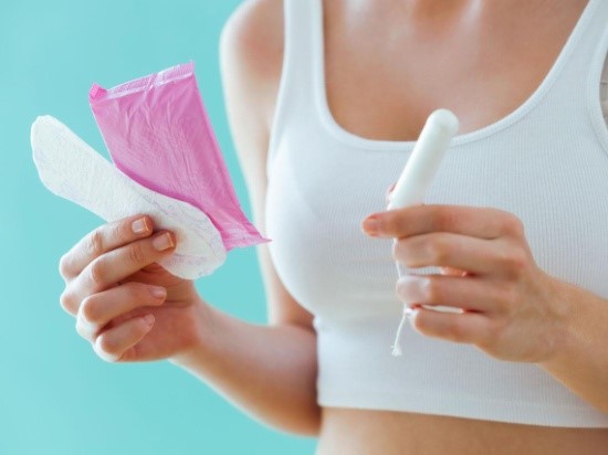 Mujer sosteniendo toallas sanitarias y tampones- síntomas de menopausia