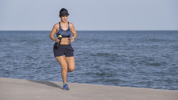mujer corriendo y ejercitando a la orilla de la playa