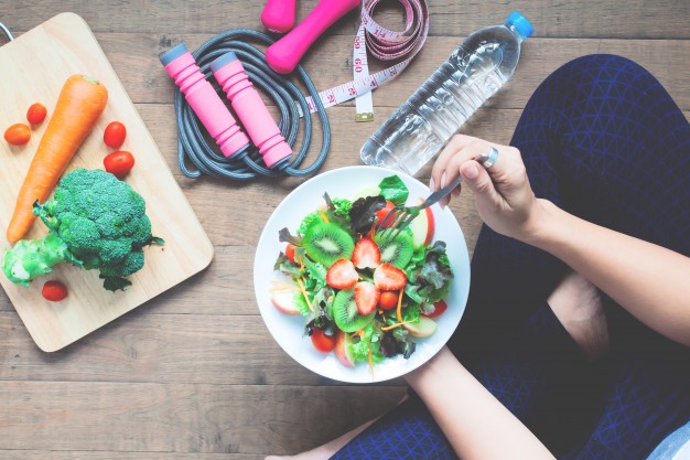 mujer sentada con plato de frutas en la mano