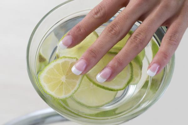 manos de mujer encima de un bol con agua y limon