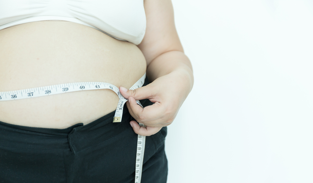 silueta de mujer midiendo su cuerpo con una cinta metrica.