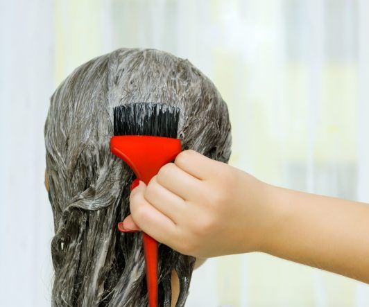 Primer plano de mujer colocandose tinte en el cabello